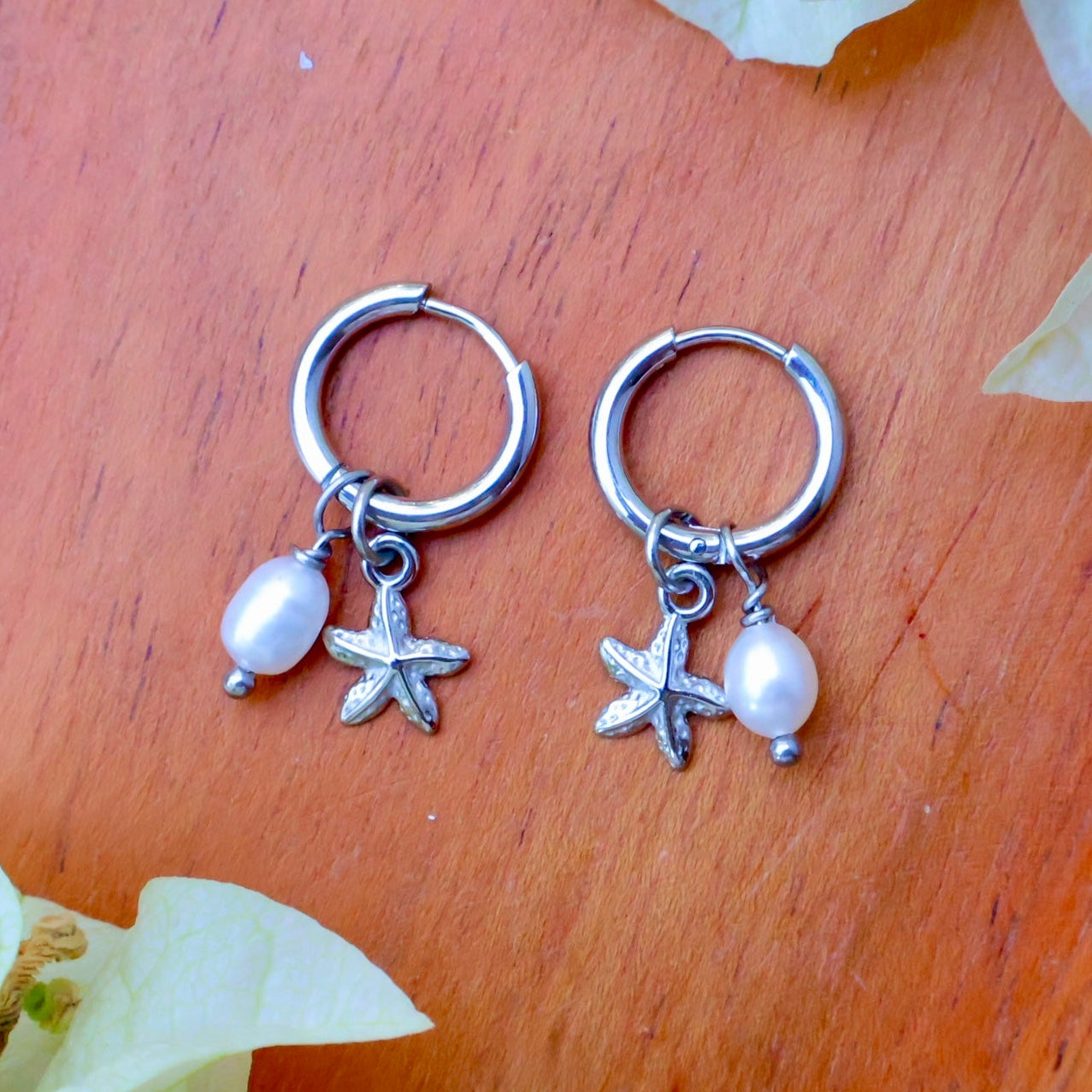 silver starfish earrings with removable charms mini starfish and freshwater pearl on a wooden background