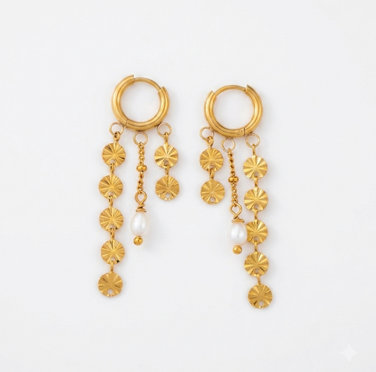 A pair of gold dangle earrings with hoop tops, hanging flower-shaped charms, and small white pearl accents, displayed on a clean white background.