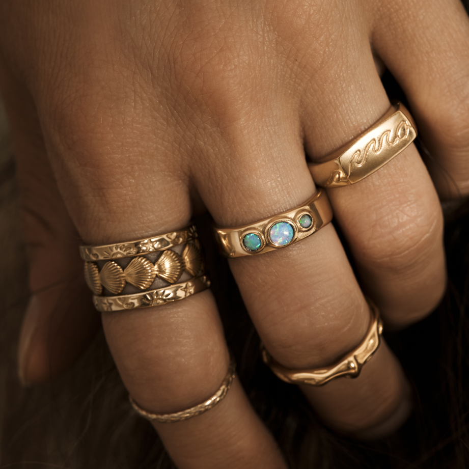 Hand showcasing various stylish Waterproof Rings featuring unique designs and opal accents.