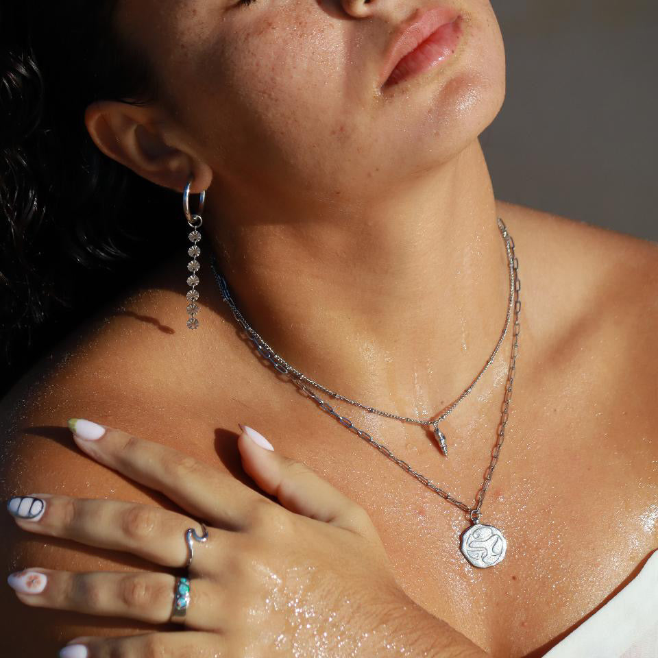 silver opal past present future ring worn with layered necklaces and earrings, showcasing a stylish beach look.