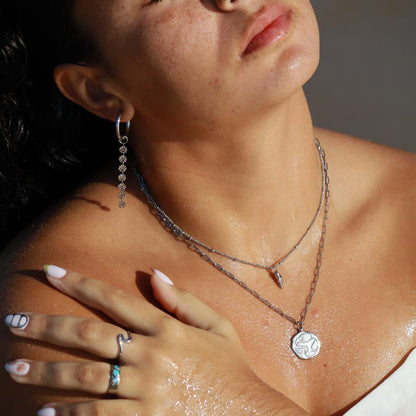 silver opal past present future ring worn with layered necklaces and earrings, showcasing a stylish beach look.
