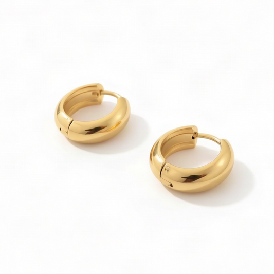 A pair of polished gold huggie hoop earrings on a clean white background.
