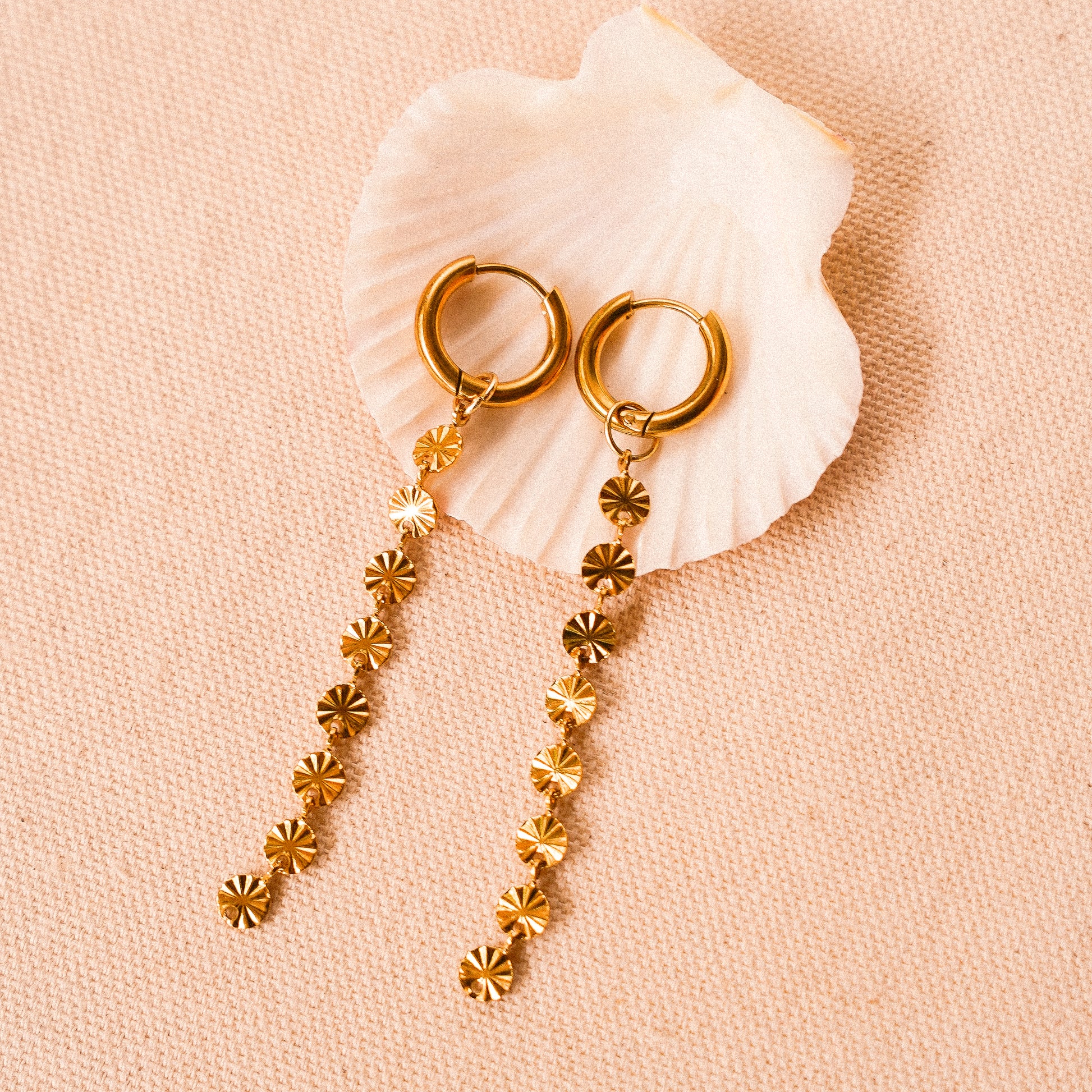 Solar inspired earrings featuring gold hoops with removable sun charms for versatile styling.