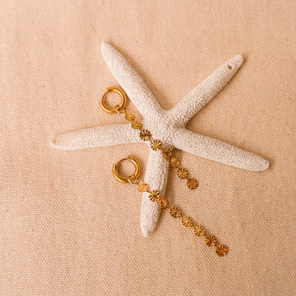 Solar inspired earrings featuring a removable sun charm on a starfish backdrop.