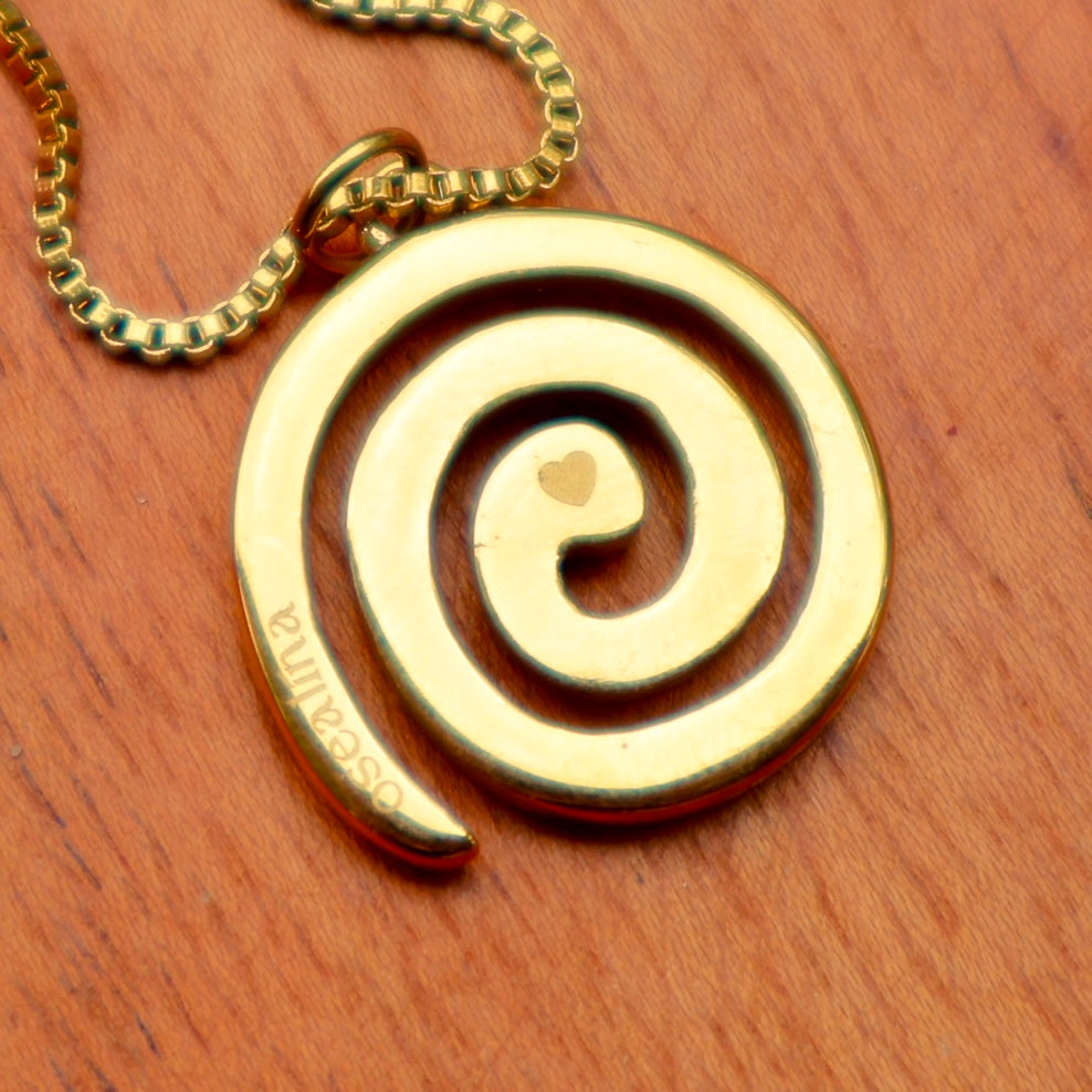 Gold spiral pendant necklace on a wooden surface