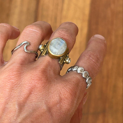 Hand wearing multiple rings with a wooden background