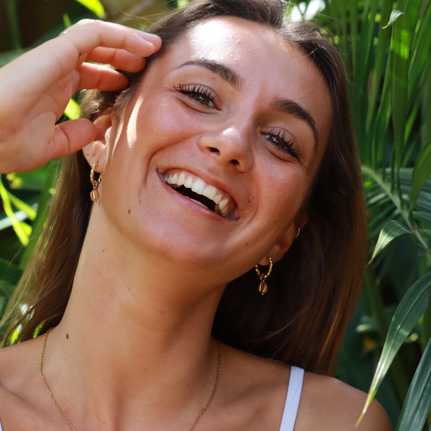 Woman with a necklace lying on green leaves