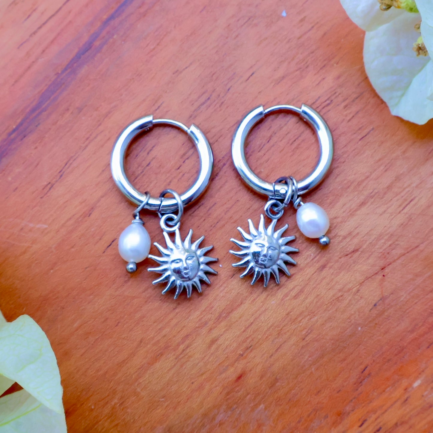 Removable charm earrings featuring a sun and pearl charm on silver hoops for versatile style.