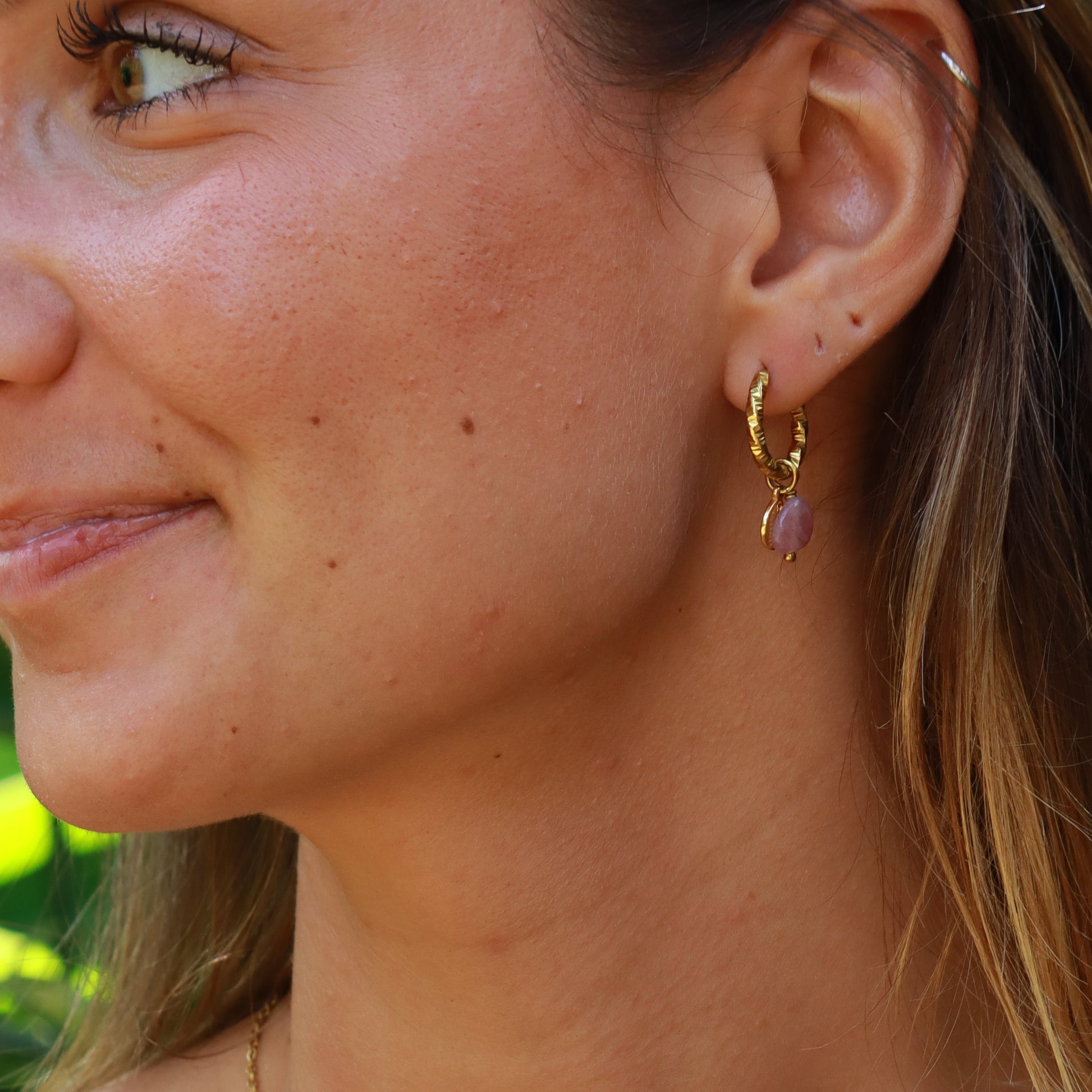 Close-up of a woman wearing a gold necklace with a green and white top.