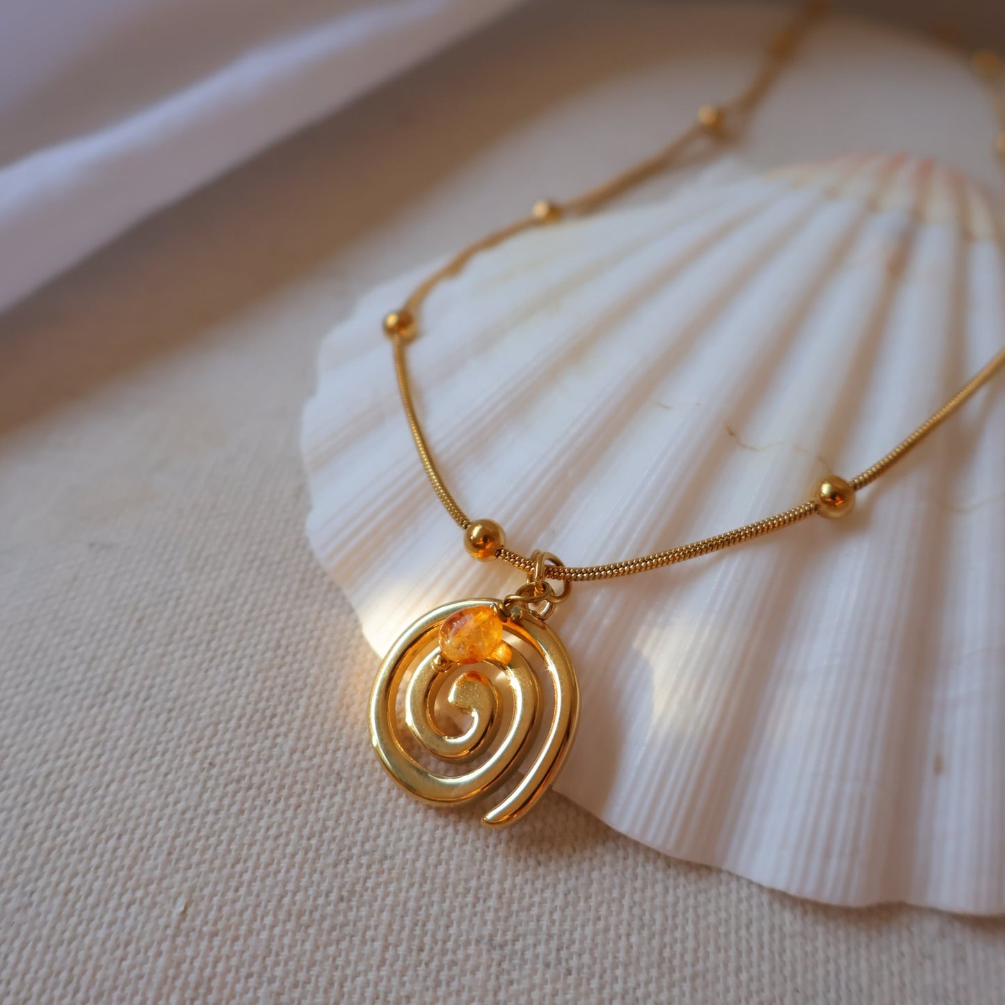 Gold necklacewith a spiral design on a white shell
