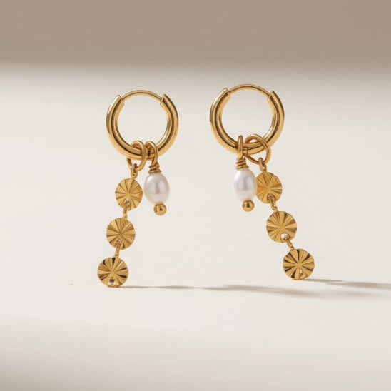 A pair of gold hoop earrings with dangling floral and bead details, displayed on a clean