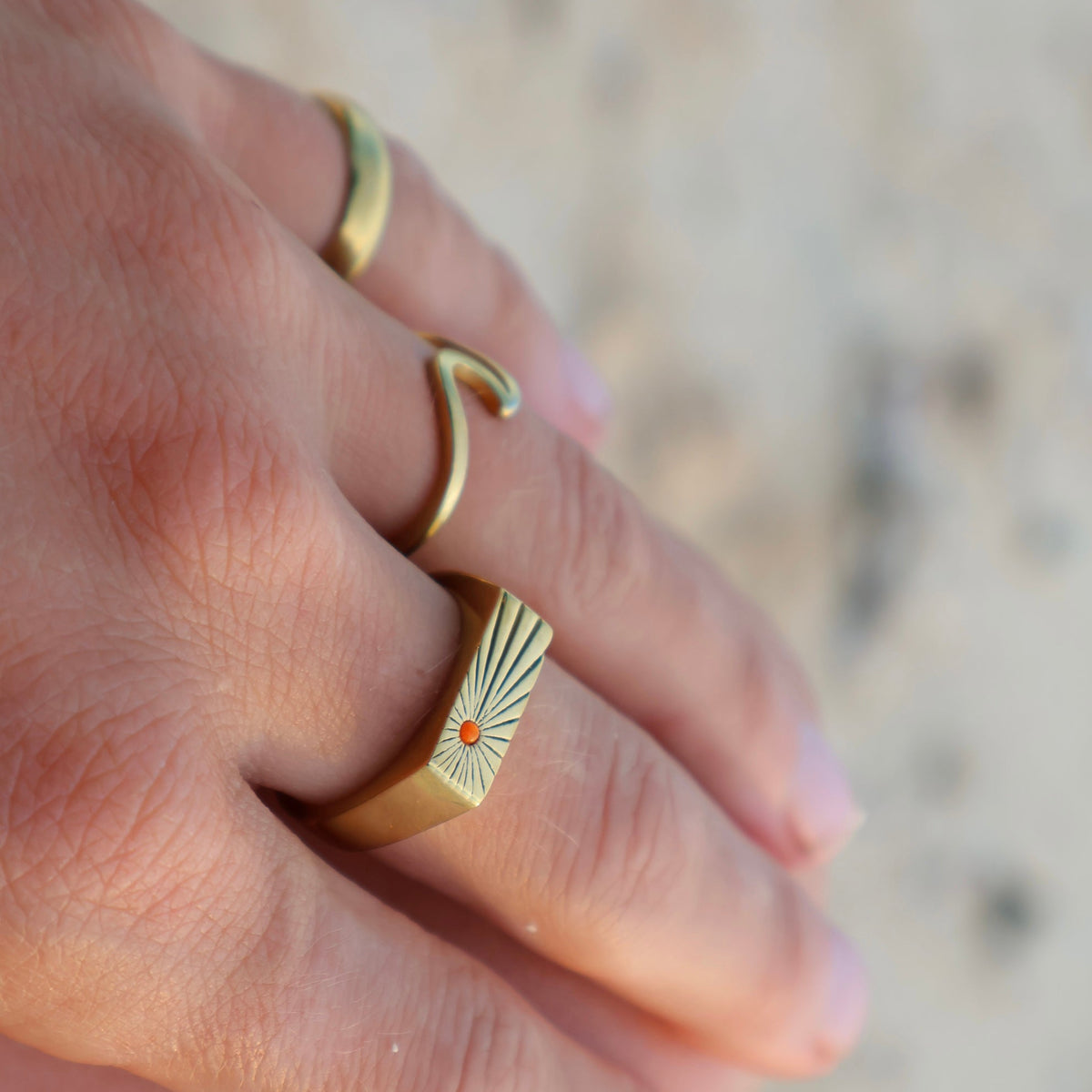Close-up of a hand wearing two gold rings with a blurred background