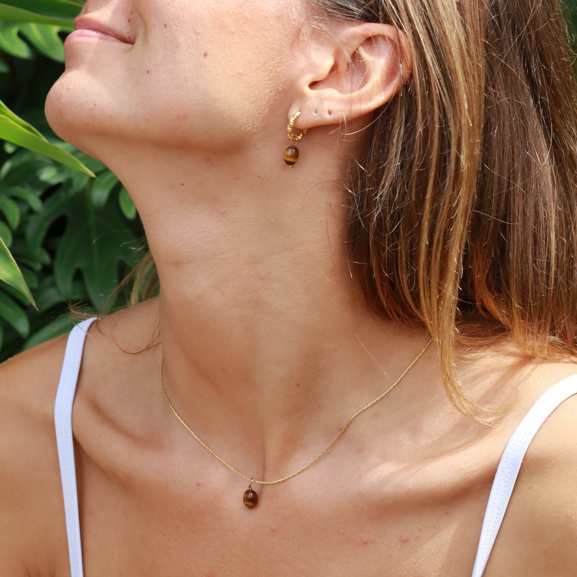 Woman lying down with a white bikini top against a green leafy background