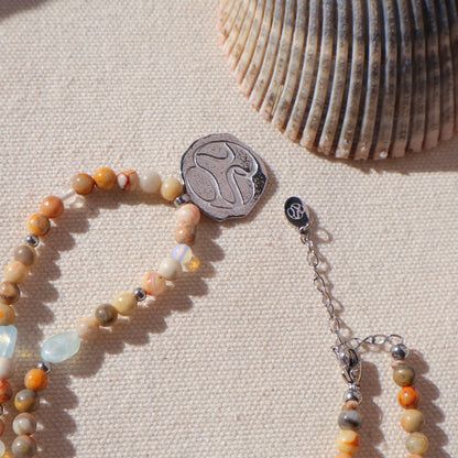 Beaded bracelet with a silver clasp on a textured beige surface