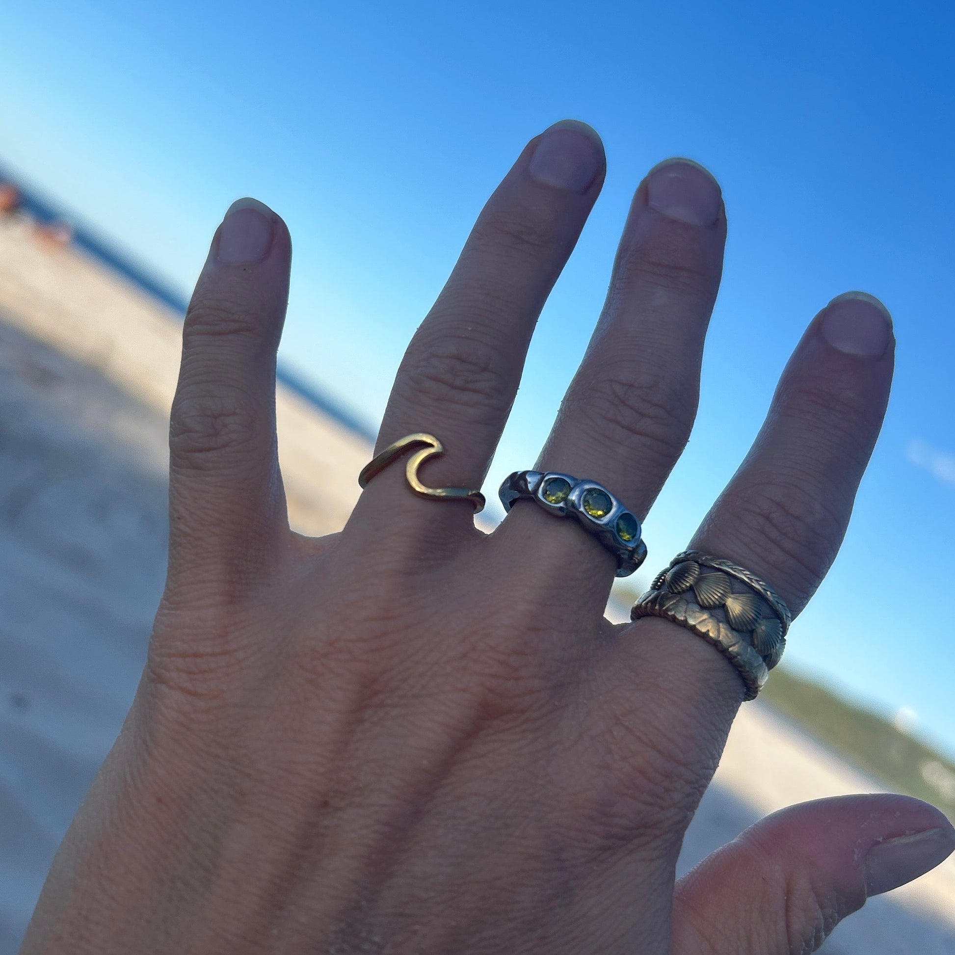 Hand with multiple rings on a beach